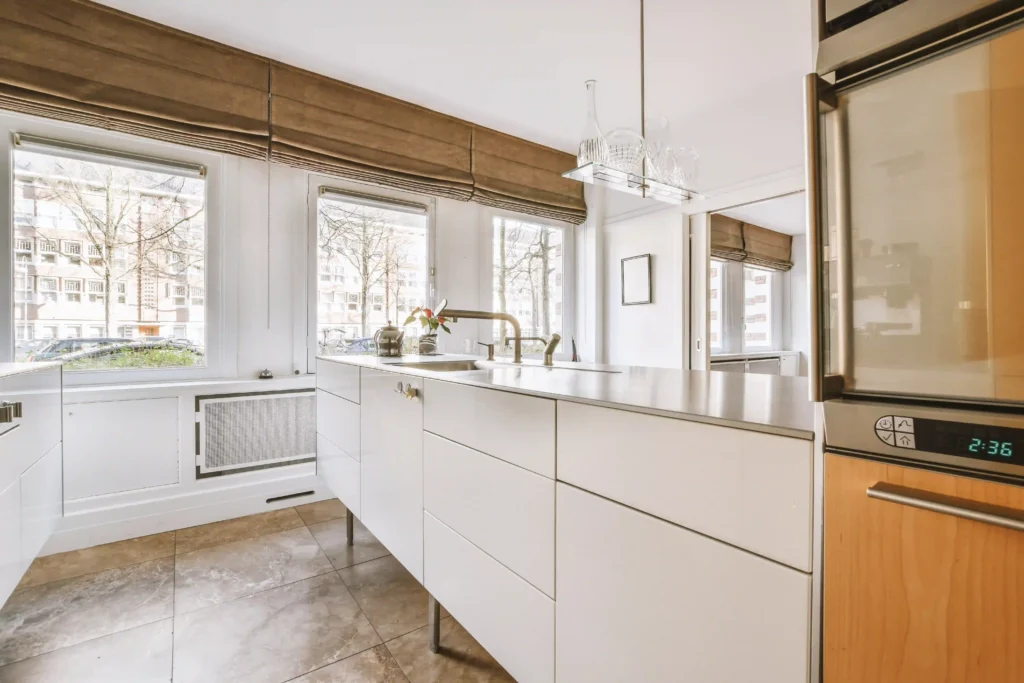 Bright white kitchen with flat-panel cabinets, a long counter and bamboo window shades