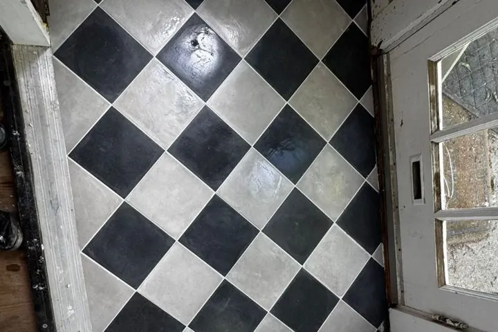 Old black and light gray checkerboard tile floor in a room under demolition