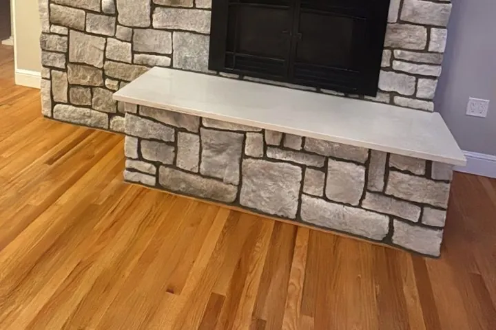 Polished hardwood floor running up to a stone-veneer fireplace